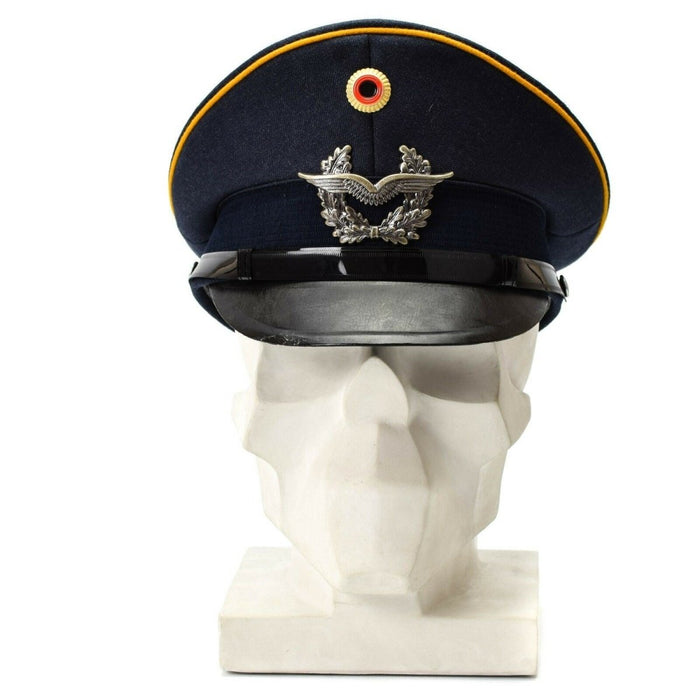 Vintage niebieska czapka z daszkiem niemieckich sił powietrznych Luftwaffe z insygniami wojskowymi i żółtą lamówką umieszczoną na białym popiersiu