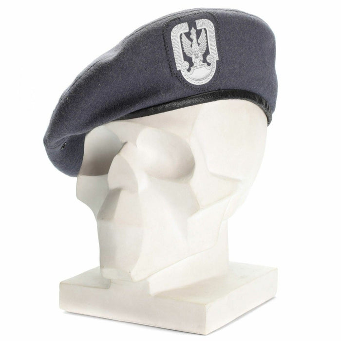 Szary wełniany beret polskiego spadochroniarza wojskowego z naszywką z przodu, eksponowany na białej głowie manekina.